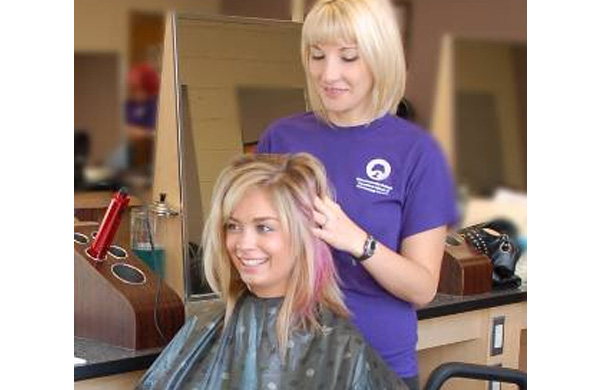 Student getting finishing touches to hair styled at Transitions School of Cosmetology