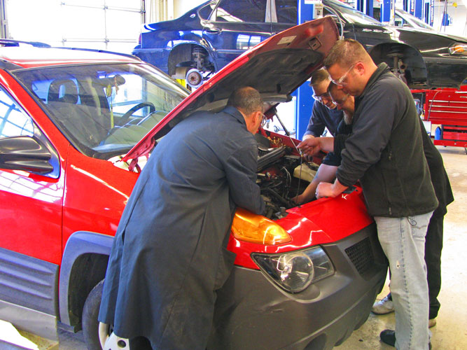 Students and instructor under the hood of a car