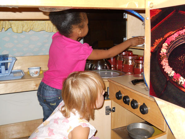 Two preschoolers Playing House by cooking in play kitchen
