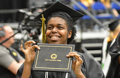 smiling female graduate holding up her diploma
