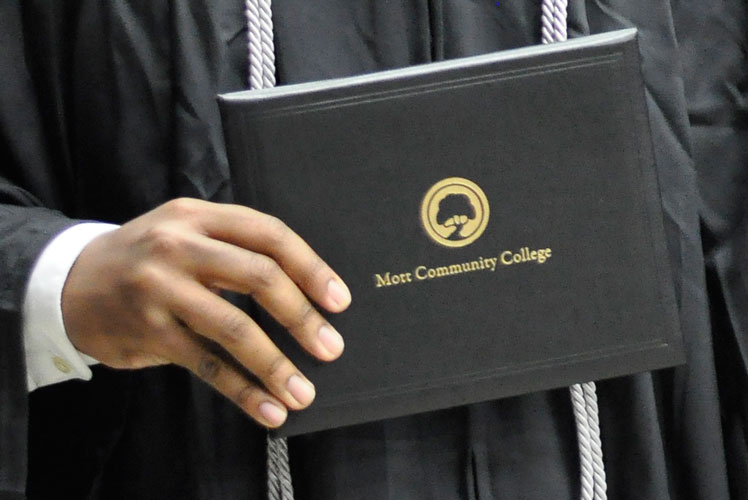 Student hand in graduation gown holding Mott Community College diploma